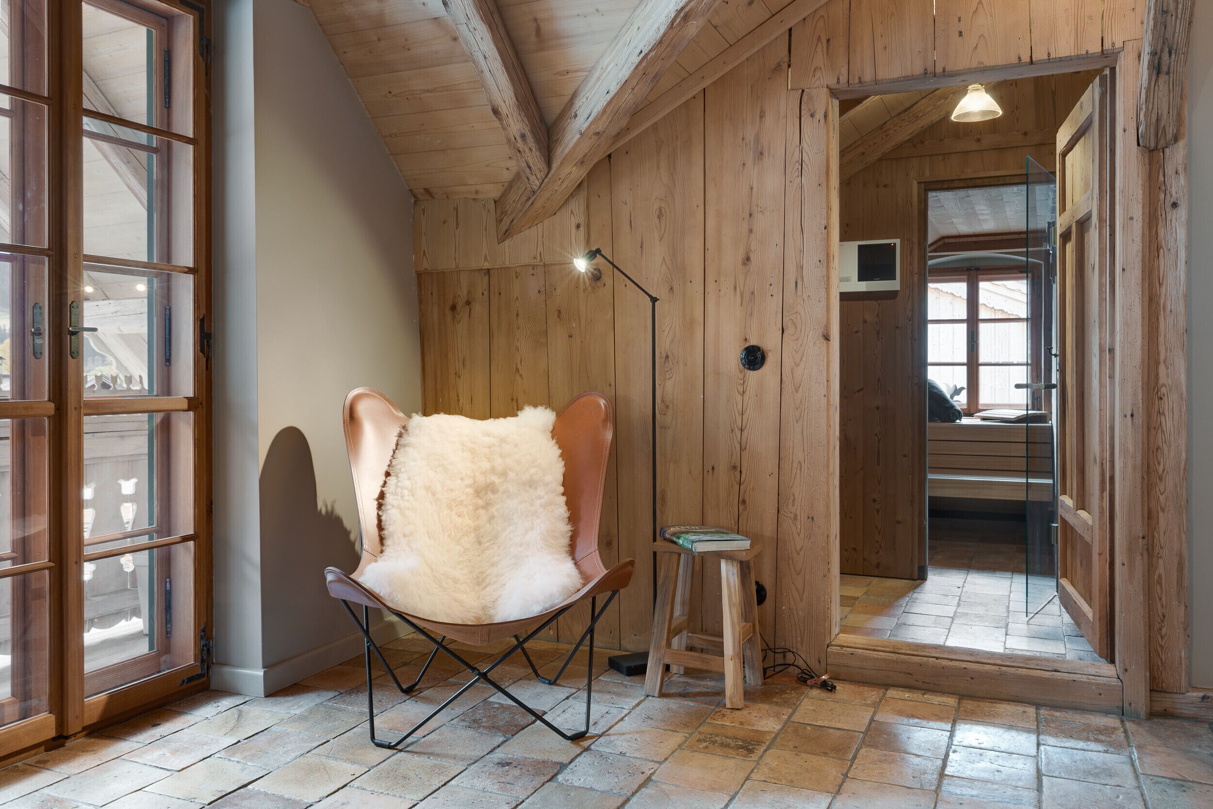 Une pièce chaleureuse avec une grande fenêtre, un plafond en bois et un fauteuil moelleux.