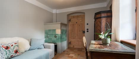 A cozy room with a sofa, a small table with a plant, and a wooden door.