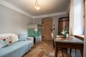 Ein gemütliches Zimmer mit einer Couch, einem kleinen Tisch mit einer Pflanze und einer Holztür.