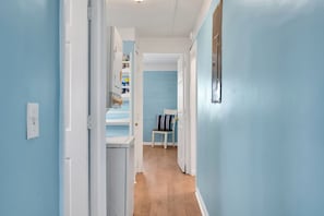 Un couloir aux murs bleu clair, aux portes blanches et au plancher en bois.