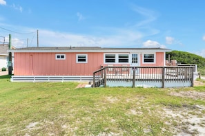 A pink single-story house with a deck and a 'NO PARKING' sign. - Cozy ocean front 3-bedroom cottage in beautiful Carolina Beach (Carolina Beach)