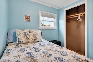 A bedroom with a bed, a window, a wooden wardrobe, and a framed picture on the wall. - Cozy ocean front 3-bedroom cottage in beautiful Carolina Beach (Carolina Beach)
