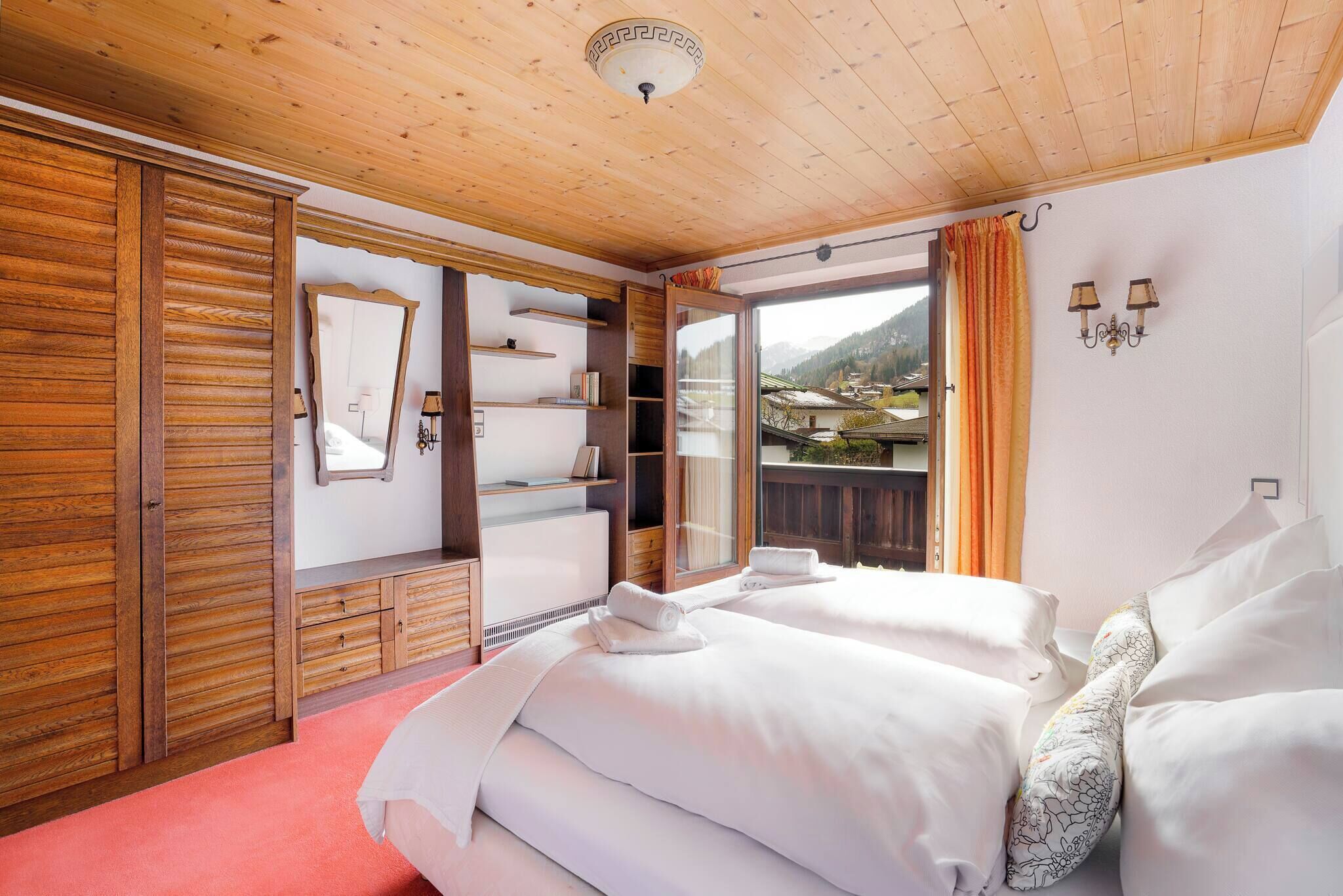 Ein Hotelzimmer mit Holzwandverkleidung, einem großen Bett, einem Kleiderschrank und Blick auf eine Berglandschaft.