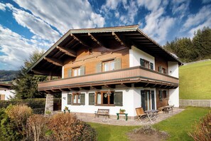 Eine zweistöckige Chalet mit Balkon, Stein Fundament und Blick auf die umliegende Landschaft.