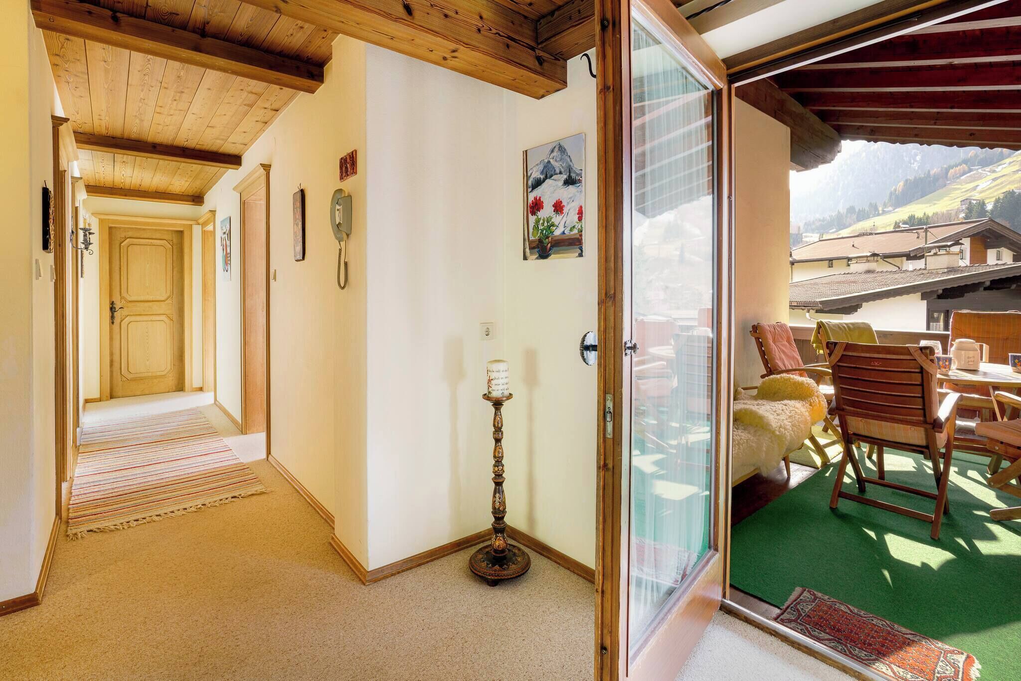 Une chambre d’hôtel avec un plafond en bois, une porte donnant sur un balcon, une table avec des chaises et un tableau au mur.