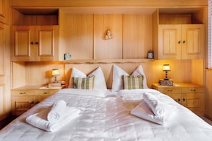 Ein Hotelzimmer mit einem großen Bett, Holzschränken, zwei Nachttischen mit Lampen und dekorativen Kissen.