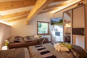 Ein Zimmer mit zwei Betten, einem Fenster mit Blick, einem Spiegel und einem Kleiderschrank.