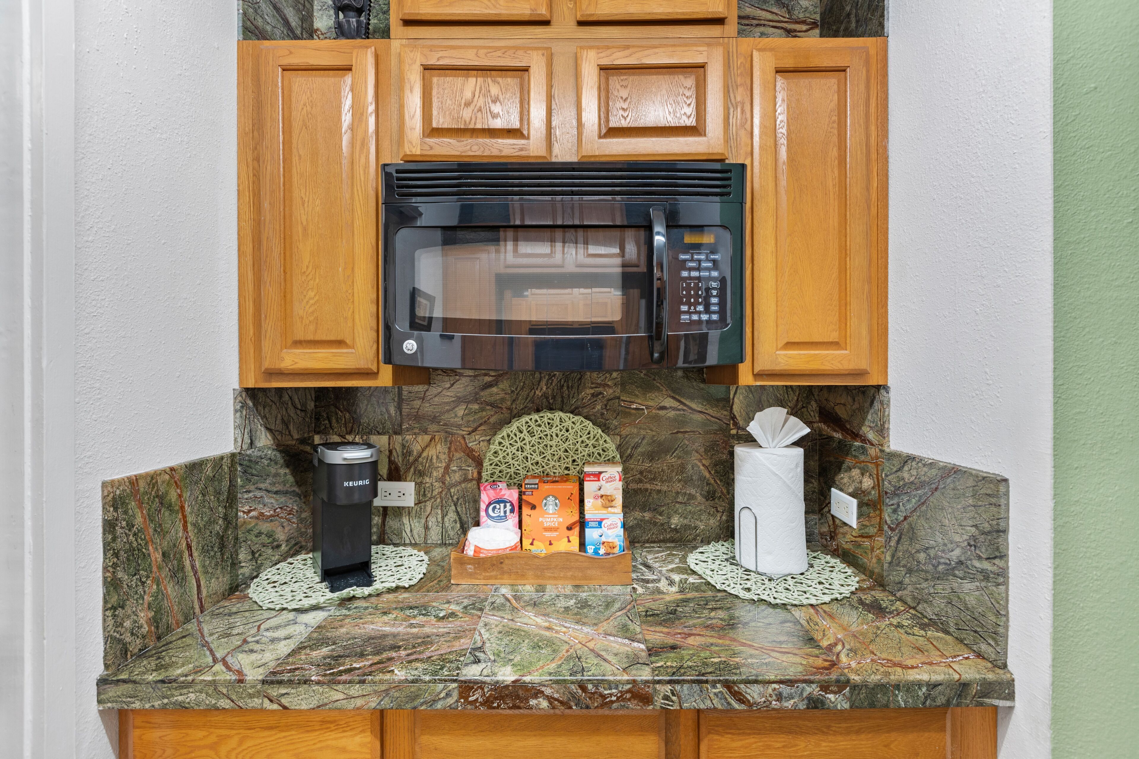A kitchen with a built-in microwave, a Keurig coffee maker, and a coffee machine on the counter.