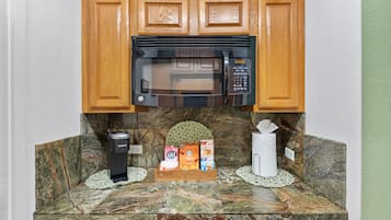A kitchen with a built-in microwave, a Keurig coffee maker, and a coffee machine on the counter.