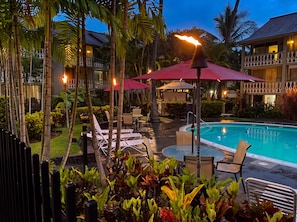 A poolside area with lounge chairs, umbrellas, and a pool. - Kailua Kona Islander | Steps to Beach, Lanai, Pool (Kailua-Kona)