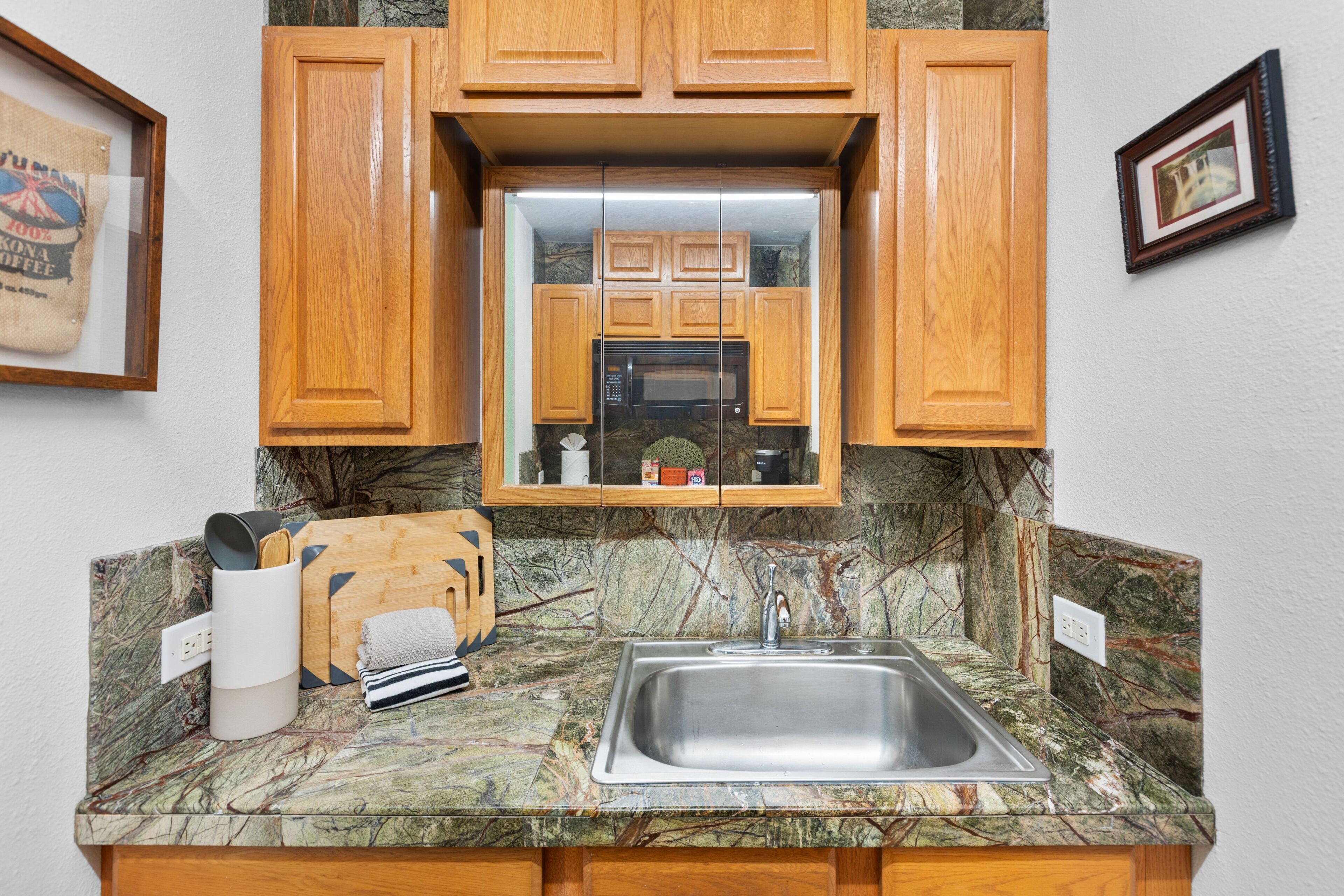 A kitchen with wooden cabinets, a stainless steel sink, and a marble countertop.