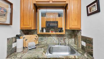 A kitchen with wooden cabinets, a stainless steel sink, and a marble countertop.