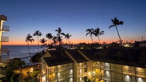 A coastal hotel with multiple floors, balconies, and a view of the ocean at sunset. - Kailua Kona Islander | Steps to Beach, Lanai, Pool (Kailua-Kona)