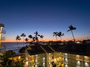 A coastal hotel with multiple floors, balconies, and a view of the ocean at sunset. - Kailua Kona Islander | Steps to Beach, Lanai, Pool (Kailua-Kona)