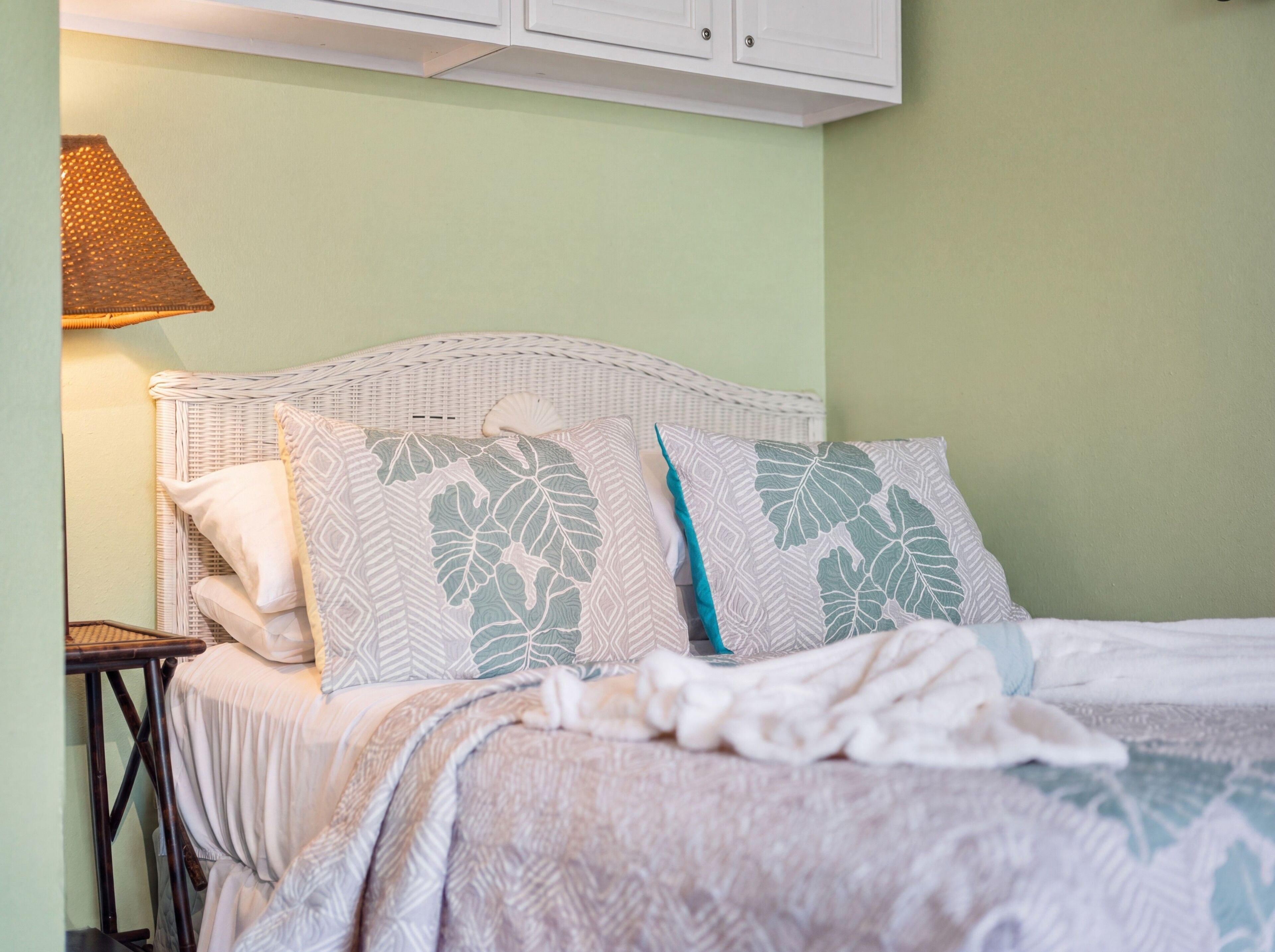 A bed with patterned pillows, a bedside table, and a lamp.