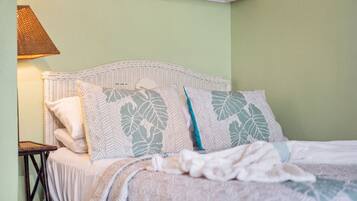 A bed with patterned pillows, a bedside table, and a lamp.