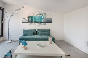 En moderne stue med en turkis sofa, et hvidt sofabord og abstrakt kunst på væggen.