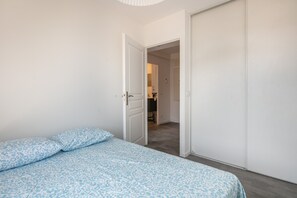 A bedroom with a bed, a wardrobe, and a door leading to a bathroom. - Le massif de Belledonne - Duplex avec terrasse (Meylan)