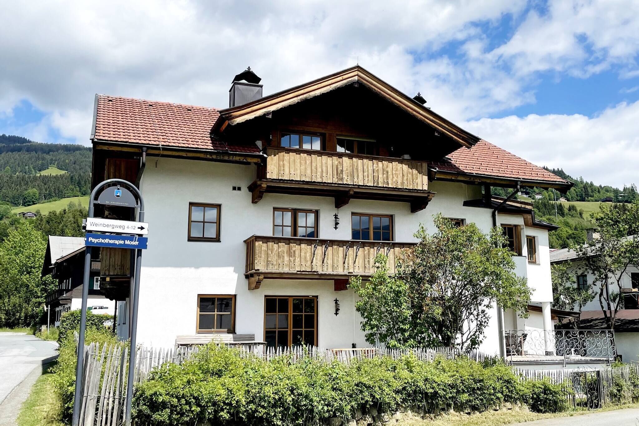 A two-story building with a white facade, wooden balconies, and a red-tiled roof.