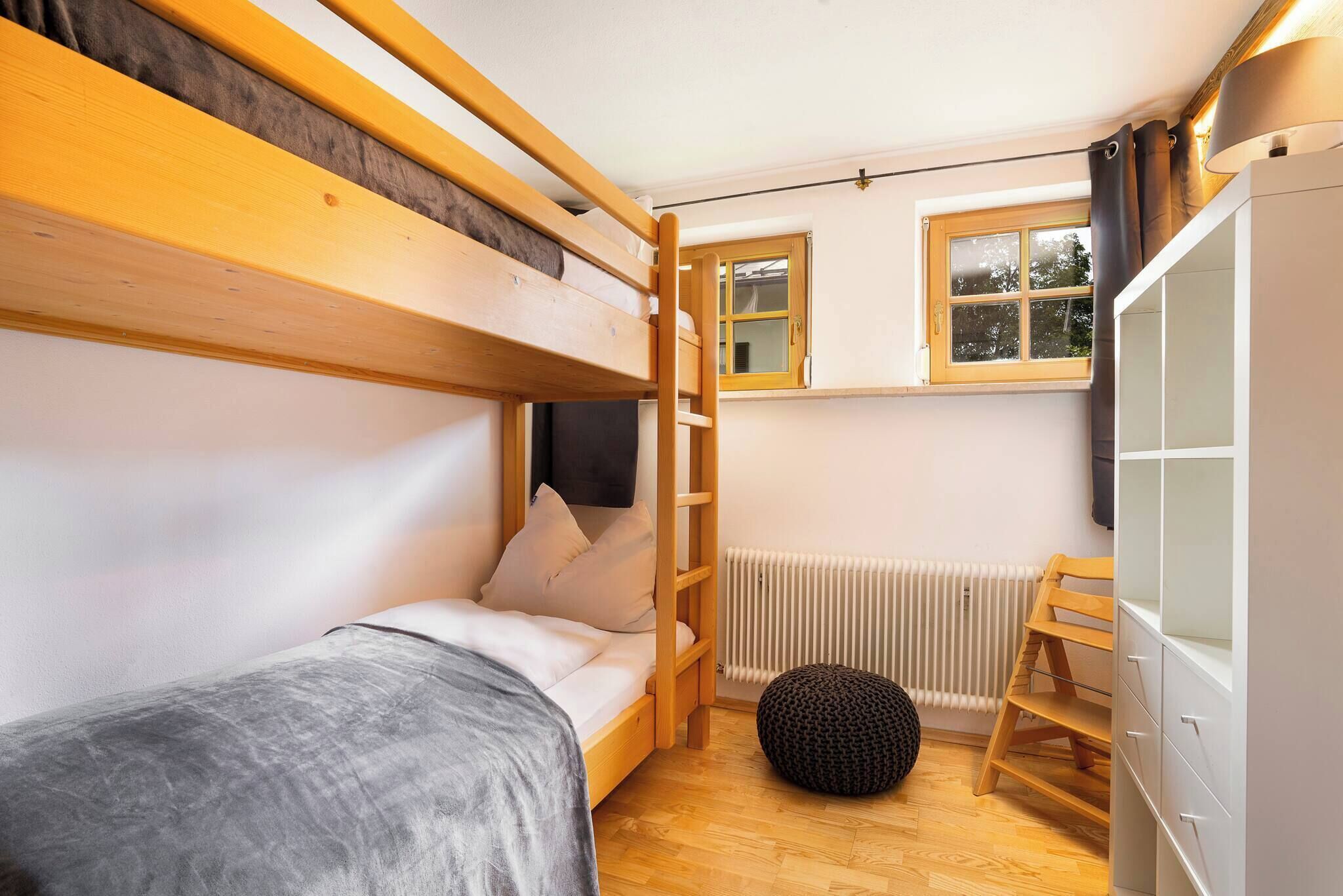 Une petite pièce avec des lits superposés, un radiateur, une fenêtre avec des rideaux et une armoire.