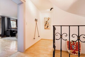 A room with a wooden floor, a black metal railing, and a wall-mounted coat rack. - KitzAlps Apartment Top 1 (Kirchberg in Tirol)