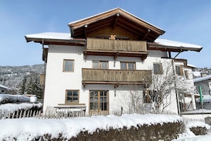 A multi-story building with a wooden facade, large windows, and a balcony. - KitzAlps Apartment Top 1 (Kirchberg in Tirol)