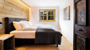 A bedroom with a bed, a window, and wooden paneling on the wall. - KitzAlps Premium Apartment (Kirchberg in Tirol)