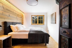 A bedroom with a bed, a window, and wooden paneling on the wall. - KitzAlps Premium Apartment (Kirchberg in Tirol)