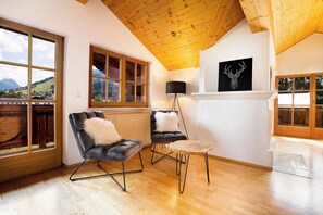 A modern interior with a wooden ceiling, two leather armchairs with fluffy pillows, a small round table, and a black lamp. - KitzAlps Apartment Top 2 (Kirchberg in Tirol)