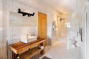 Une salle de bain moderne avec un meuble-lavabo en bois, un grand miroir, une douche et des toilettes.