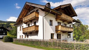 A two-story building with wooden balconies and a white facade. - KitzAlps Premium Apartment (Kirchberg in Tirol)