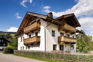 A two-story building with wooden balconies and a white facade. - KitzAlps Premium Apartment (Kirchberg in Tirol)
