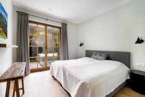 A bedroom with a large bed, a desk, and a window with curtains. - Garden Suite by Alpine Host Helpers (Kirchberg in Tirol)