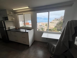 Eine Küche mit Fenster, einem Stuhl und Blick auf Gebäude.