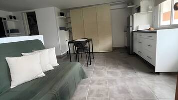 Ein zeitgemäßer Wohnraum mit einem grünen Sofa, einem Esstisch und einer Küchenzeile.