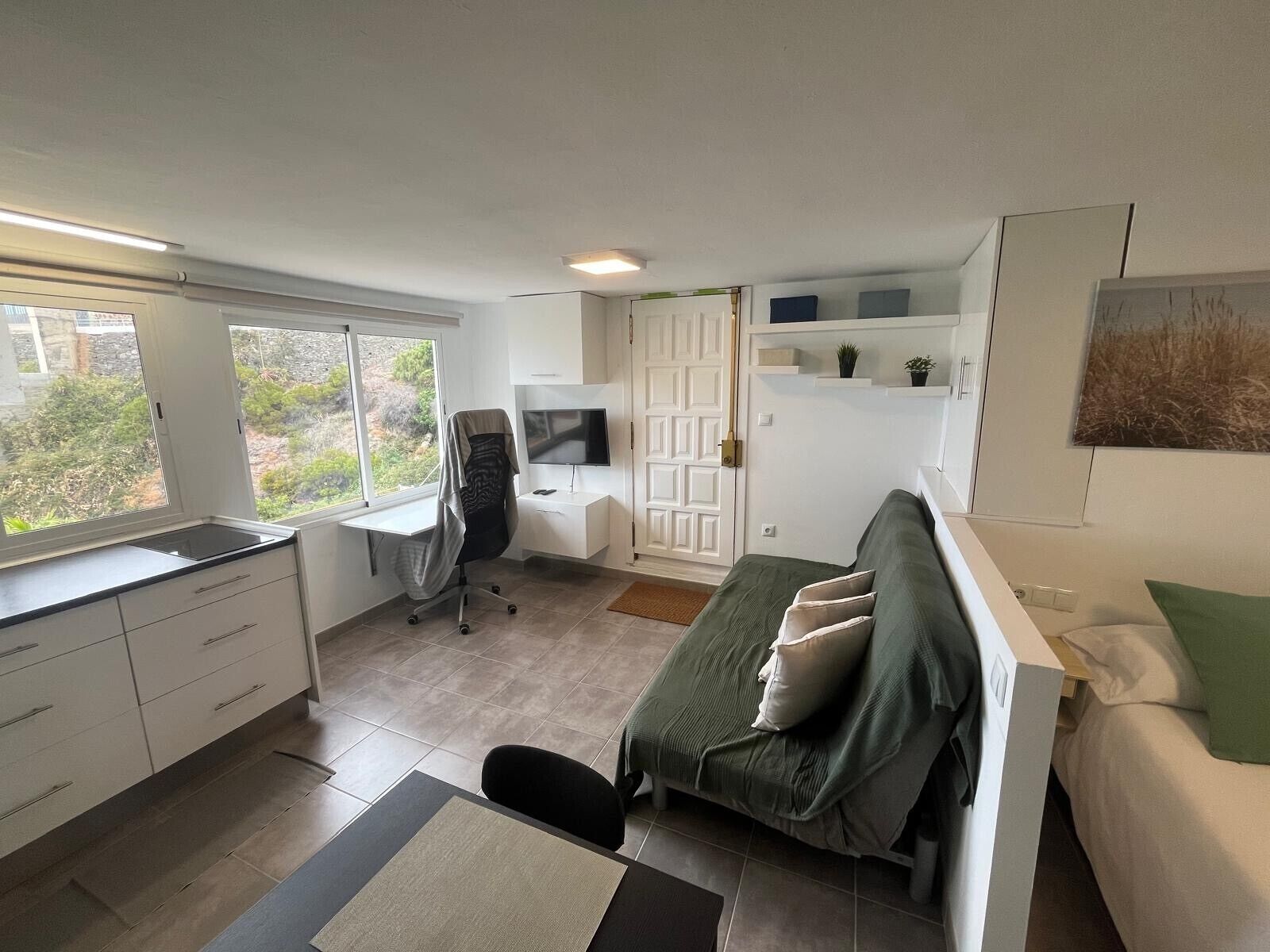 Een moderne slaapkamer met een bed, bureau en televisie.