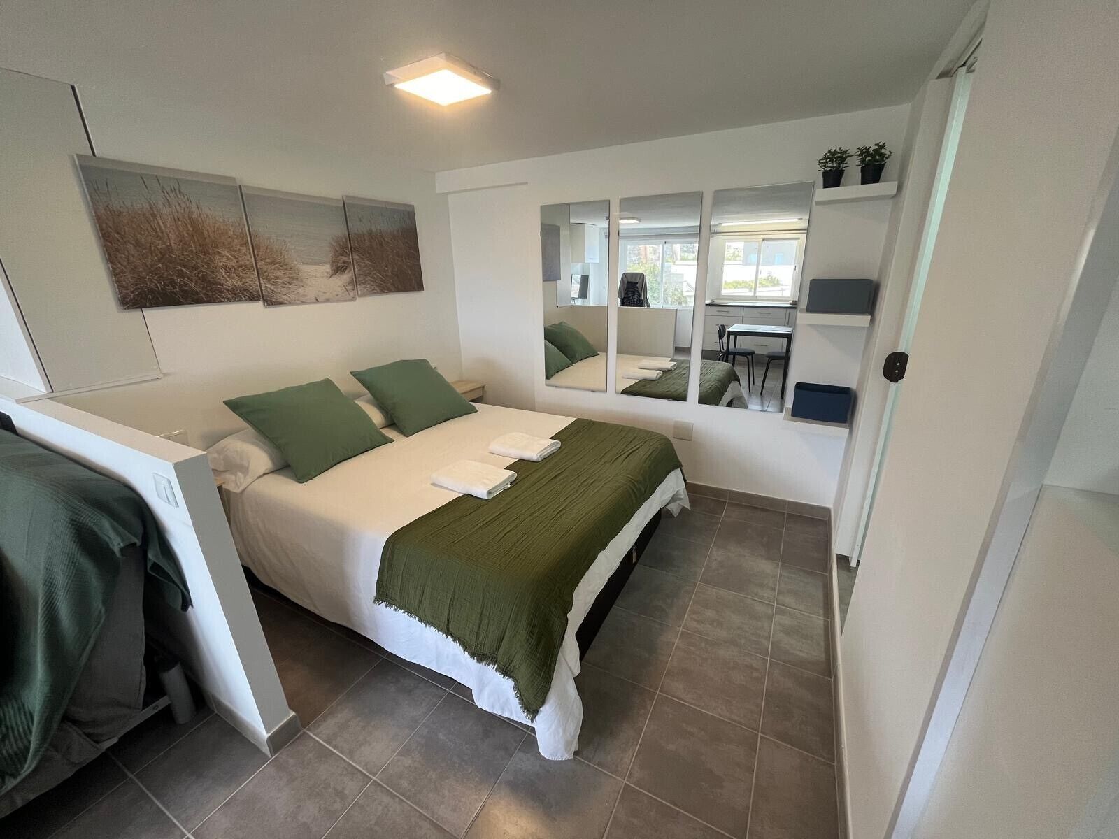 Una habitación con una cama, un escritorio y una silla. Hay una ventana y una puerta.