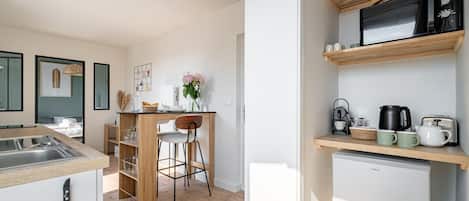 A modern kitchen with a built-in microwave, a refrigerator, and a wooden bar counter.