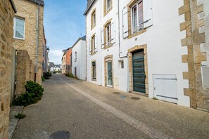 A narrow cobblestone street flanked by historic stone buildings with traditional shutters and doors. - Le Carré des Skippers - Sur les quais du port (La Trinite-sur-Mer)