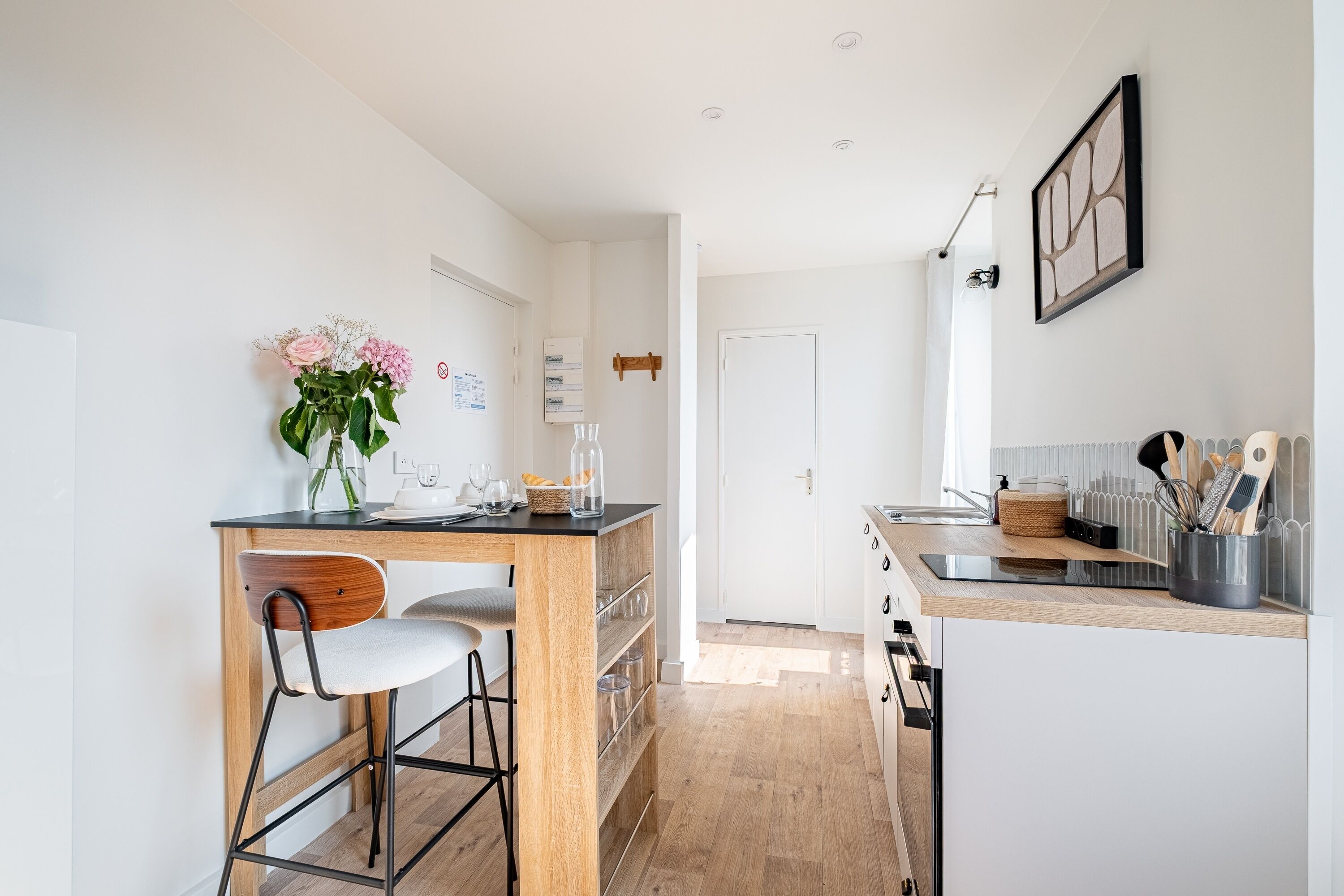 A modern kitchen with a wooden island, bar stools, and a vase of flowers.