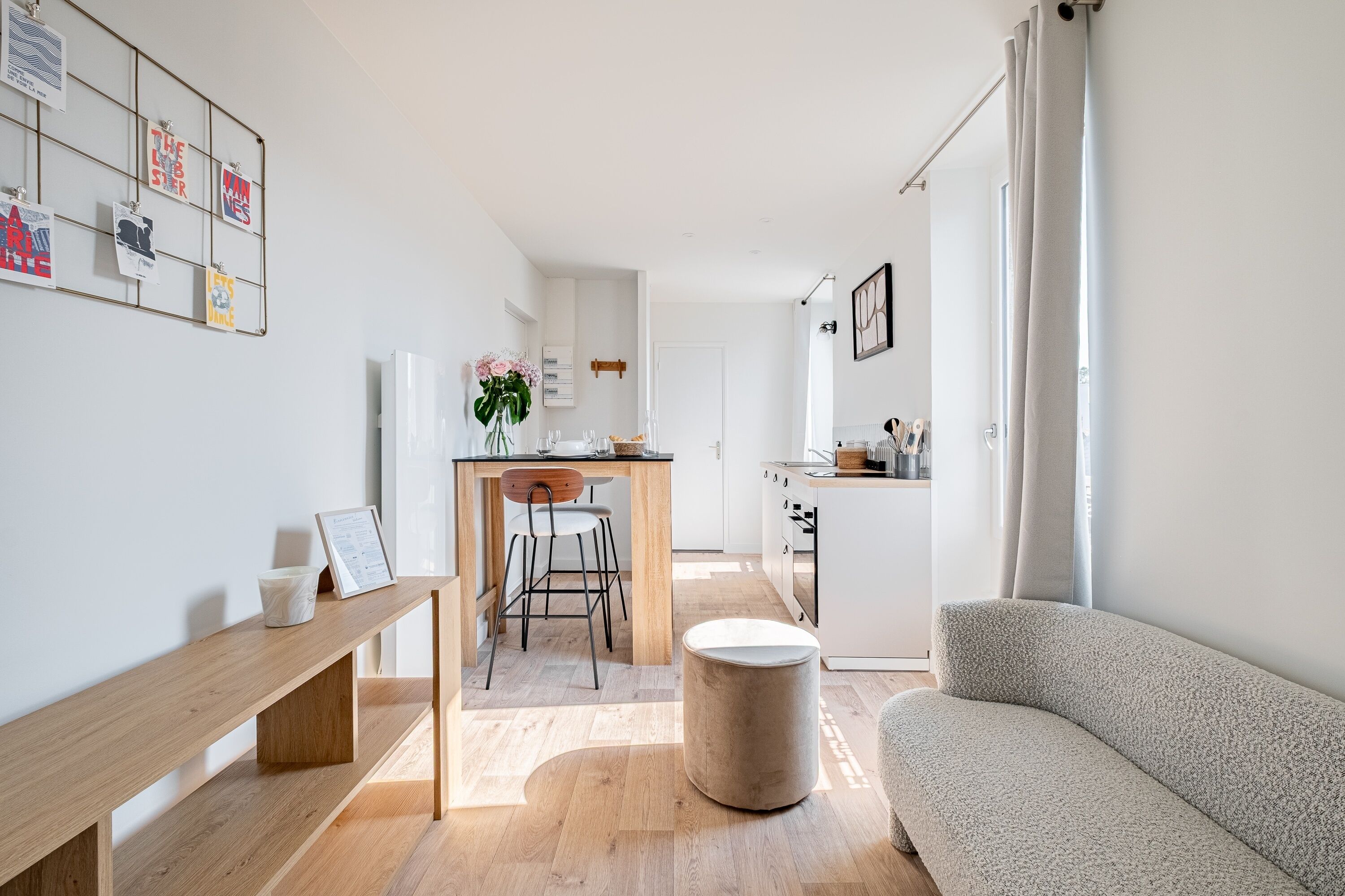 A modern kitchen with a central island, a dining area with a bench, and a living room with a sofa.