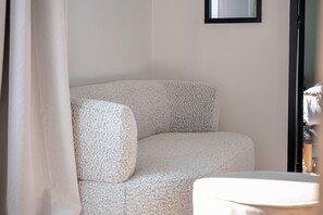 A corner of a room with a white textured sofa and a small table. - Le Carré des Skippers - Sur les quais du port (La Trinite-sur-Mer)