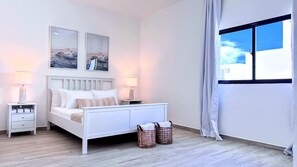 A bedroom with a bed, two bedside tables, a window with curtains, and two wall-mounted picture frames. - Private Rooftop Plunge Pool Sun Deck Beaches BBQ (Punta Cana)