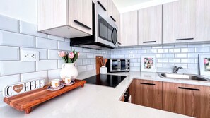 A modern kitchen with light wood cabinets, a black microwave, a stainless steel sink, and a wooden countertop with a coffee setup. - Private Rooftop Plunge Pool Sun Deck Beaches BBQ (Punta Cana)