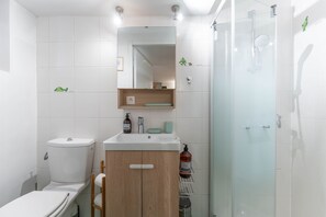 Une salle de bain moderne équipée de toilettes, d’un lavabo, d’un miroir et d’une douche.