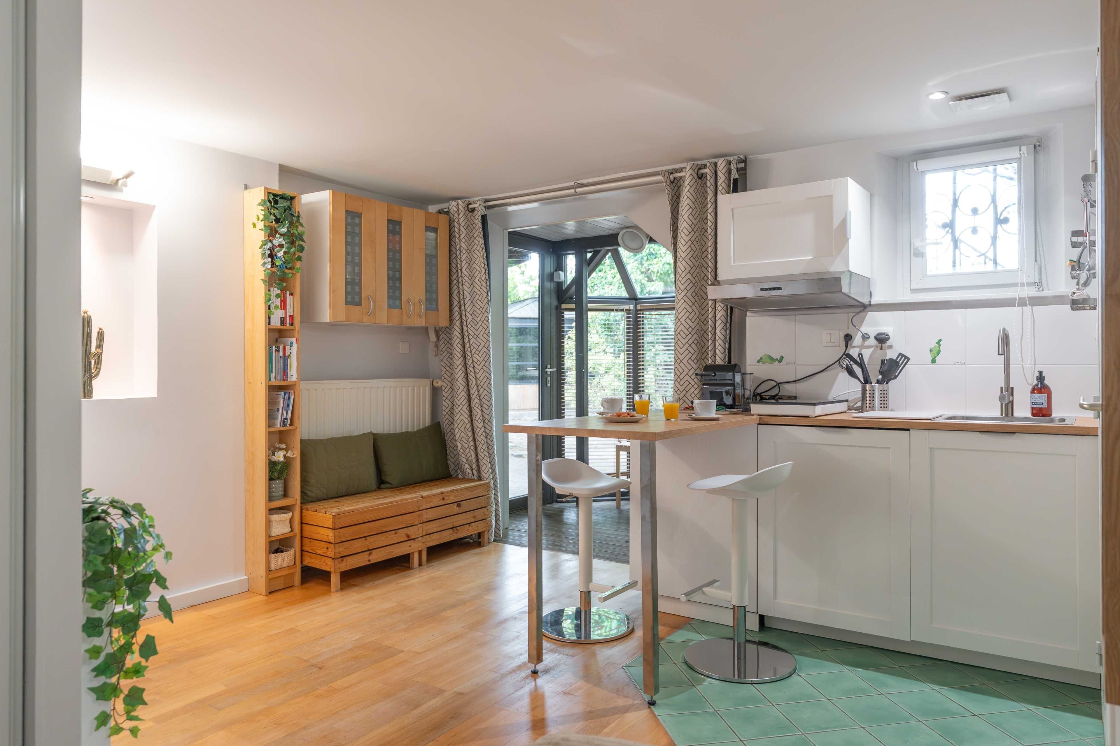 A modern kitchen with a wooden bench, a bar stool, and a dining table.