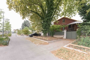 A residential street with a parked car, a bench, and a large tree. - Le Cottage - Studio avec véranda et jardin (Lyon)