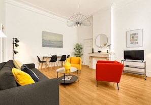 Una sala de estar moderna con un sofá, un sillón rojo, una mesa de centro y un televisor.