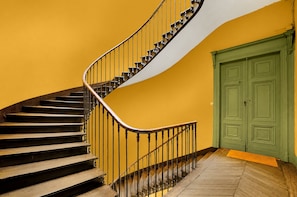 Eine Wendeltreppe mit Metallgeländer, das zu einer grünen Tür führt.