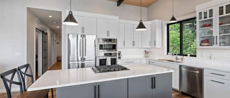 A modern kitchen with a central island, stainless steel appliances, and pendant lighting.
